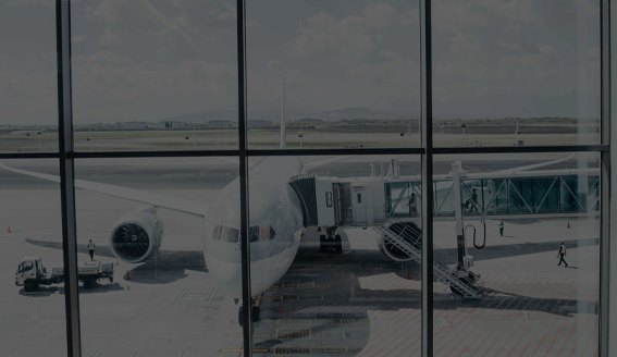 An airliner on stand at a terminal gate, seen through the terminal glass
